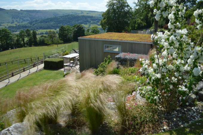 Terraced garden with boulders, grasses and garden room