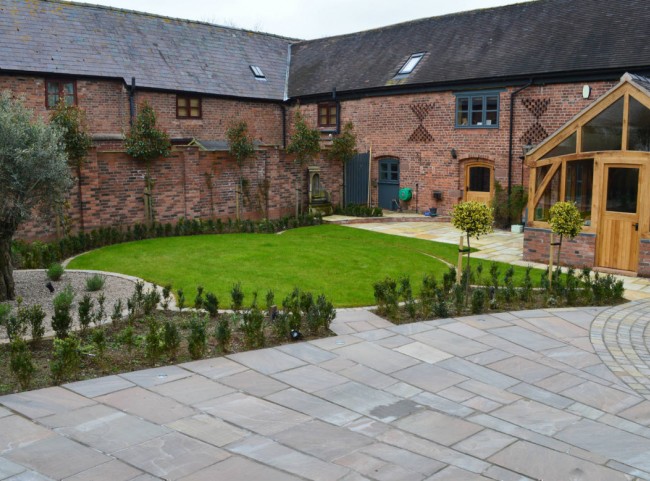 Courtyard garden with natural stone paving and circular lawn