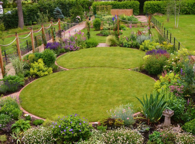 Circular lawns and traditional planting. Timber posts support ropes on to which roses and clematis will climb.