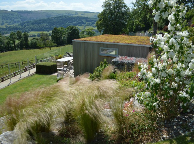 Terraced garden with boulders, grasses and garden room
